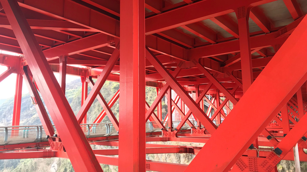 矮寨大桥是一座双层桥梁,红色钢架顶部是四车道的高速公路,红色钢架