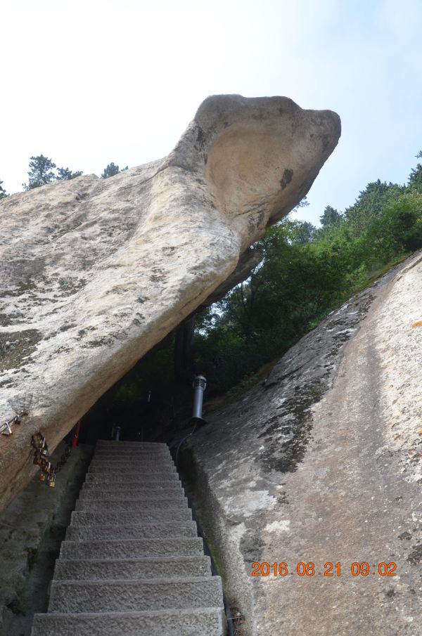 这里东西两岩相对而出,中间形成槽沟,东岩前倾悬空如覆,岩壁布满石窝