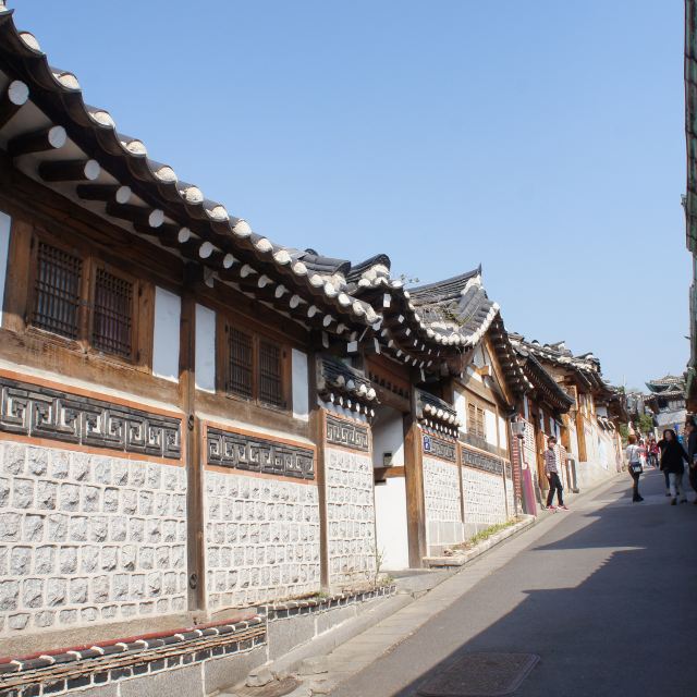 我们从南山谷韩屋村出来,再次打的来到北村韩屋村。北村与南山谷韩屋村不同的地方在于:这儿是韩屋聚集的住宅区,生活气息浓郁。正值周日早晨,北村似乎还没有从慵懒中苏醒过来,到此的客人也自觉保持着安静,在宁静的气氛中感受闲暇。就像韩剧中表现的一样,这儿的街道窄窄的,有着一定的坡度,不管是门头、院墙,都保留了韩屋的鲜明特征。沿坡而筑的屋檐连成一条龙脊,低矮的院墙用瓦片装饰出古朴的图案,拾阶而上,看见无数的韩屋屋顶重重叠叠。 北村的推广活动也做得很好,除了设立旅游咨询处,还有身穿红衣的志愿者守候在叉路口,为游客指路解