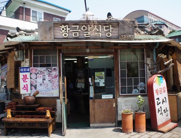 我们从南山谷韩屋村出来,再次打的来到北村韩屋村。北村与南山谷韩屋村不同的地方在于:这儿是韩屋聚集的住宅区,生活气息浓郁。正值周日早晨,北村似乎还没有从慵懒中苏醒过来,到此的客人也自觉保持着安静,在宁静的气氛中感受闲暇。就像韩剧中表现的一样,这儿的街道窄窄的,有着一定的坡度,不管是门头、院墙,都保留了韩屋的鲜明特征。沿坡而筑的屋檐连成一条龙脊,低矮的院墙用瓦片装饰出古朴的图案,拾阶而上,看见无数的韩屋屋顶重重叠叠。 北村的推广活动也做得很好,除了设立旅游咨询处,还有身穿红衣的志愿者守候在叉路口,为游客指路解