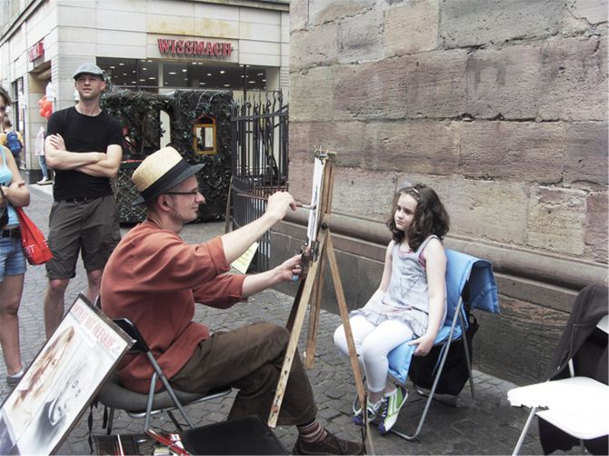 画肖像的街头画家,在给小姑娘画素描