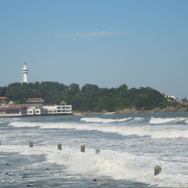 从第一海水浴场看烟台山,白塔在绿树丛里显得更加挺拔,近处,海浪一波